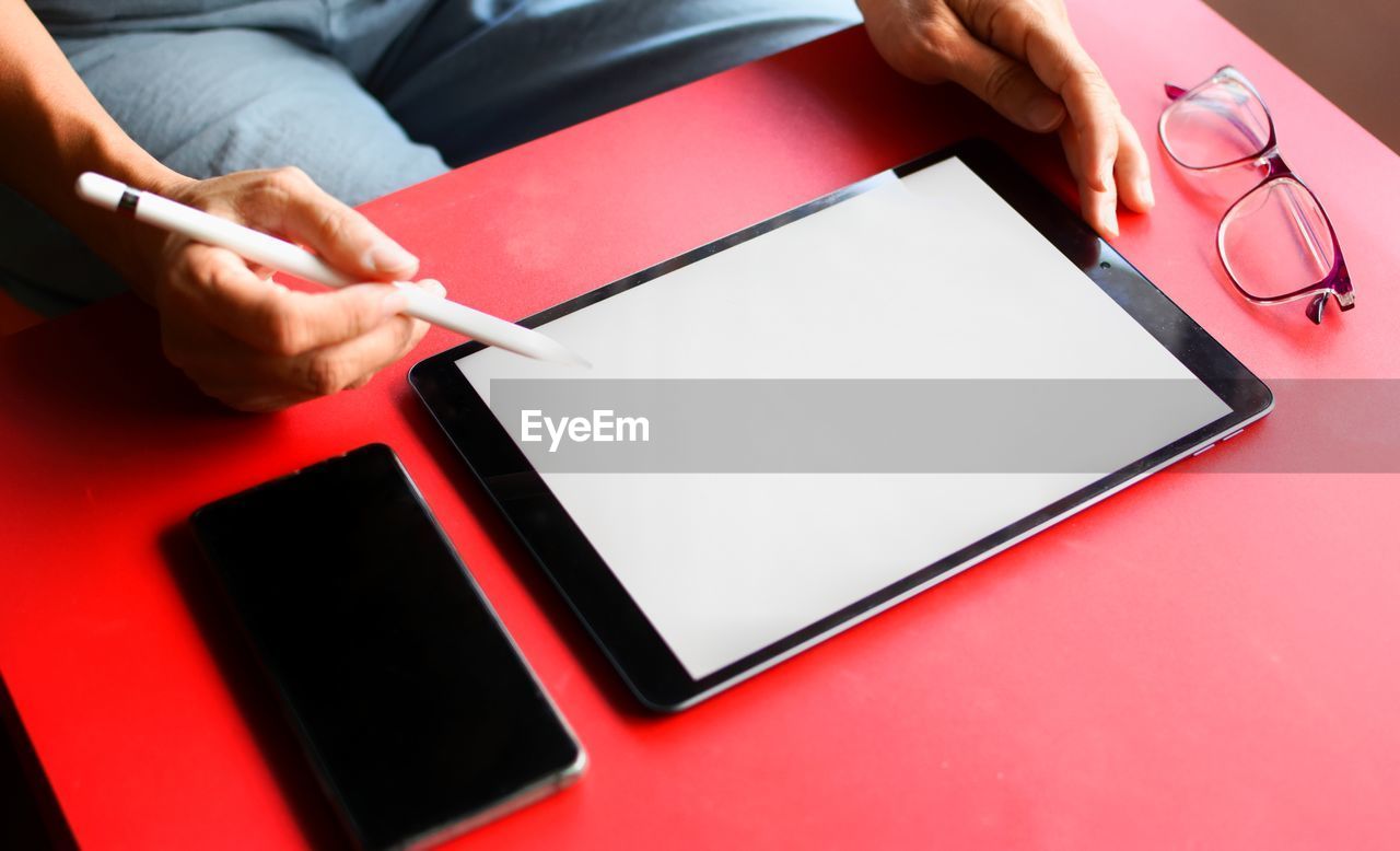 Midsection of person holding smart phone on table