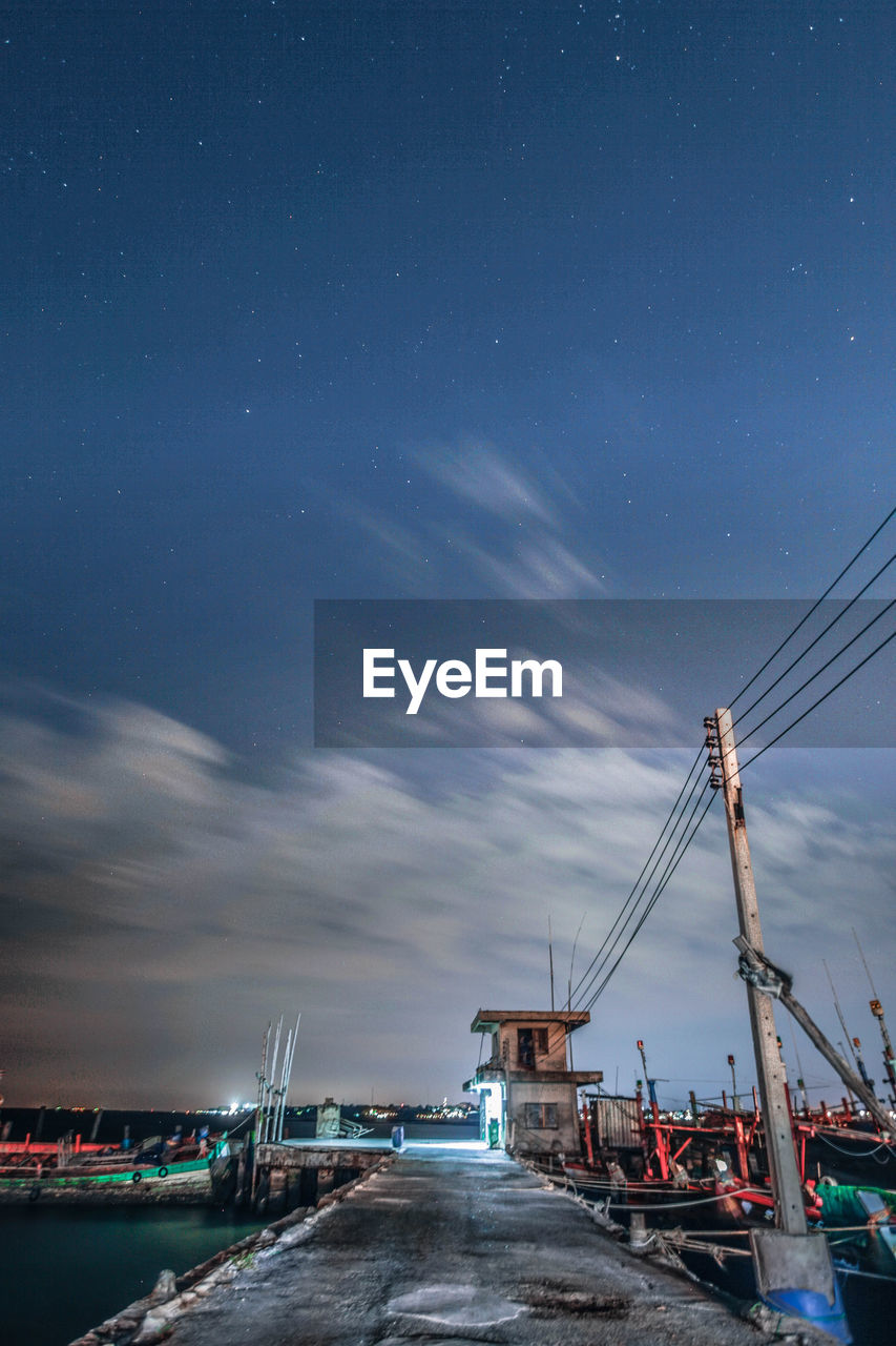 Illuminated pier by sea against sky at night