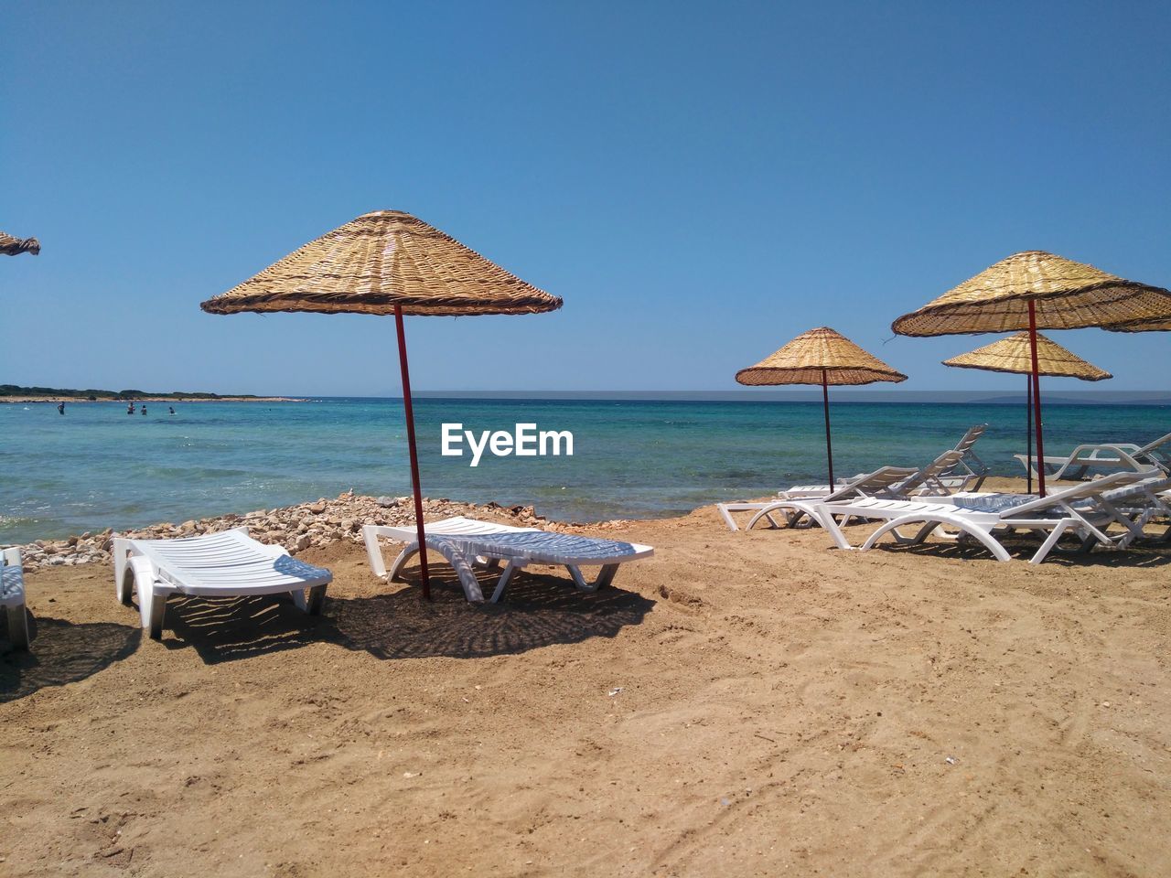 DECK CHAIRS ON BEACH AGAINST SKY