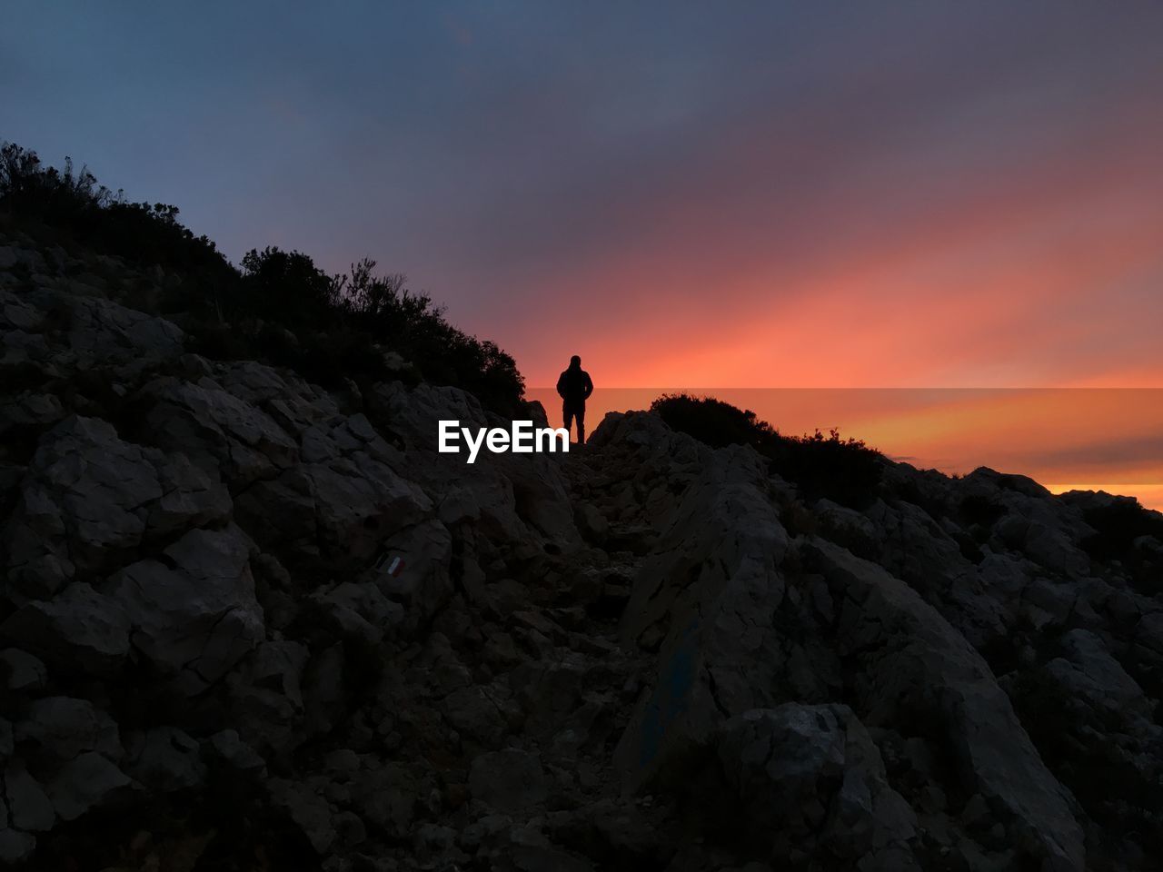 Silhouette man standing on cliff against sky during sunset