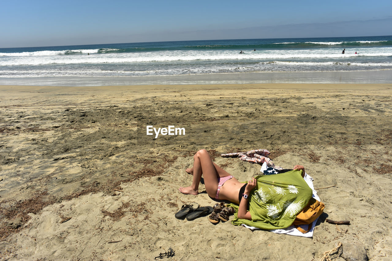 WOMAN LYING ON SAND AT BEACH