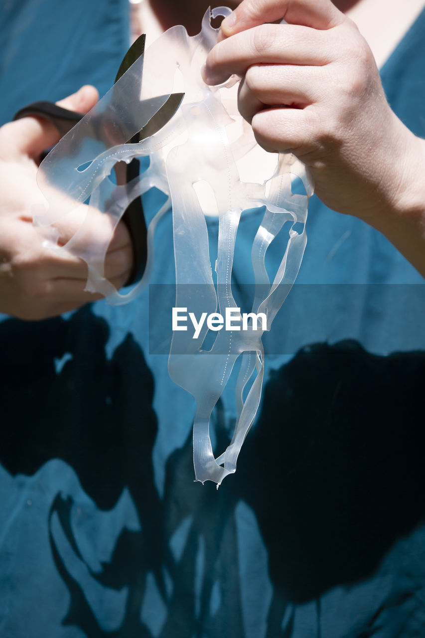 Midsection of woman cutting plastic