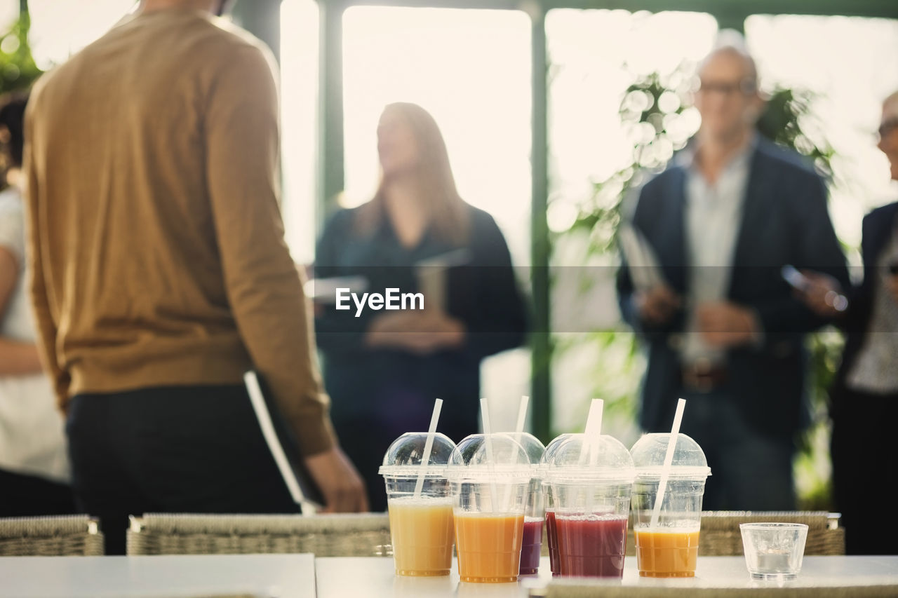 Fruit juice in plastic cups on table with business people in background at office