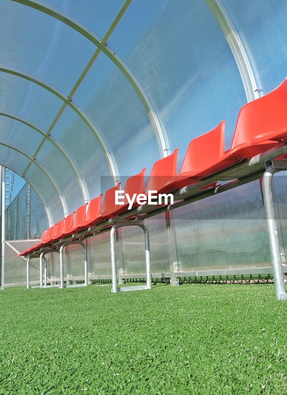 Low angle view of empty red seats on soccer field