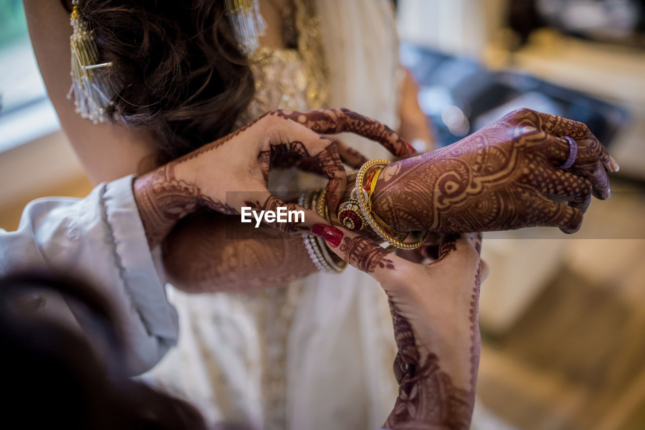 Hand of an indian bride decorated with henna or mehndi wearing gold bangle made with diamond 