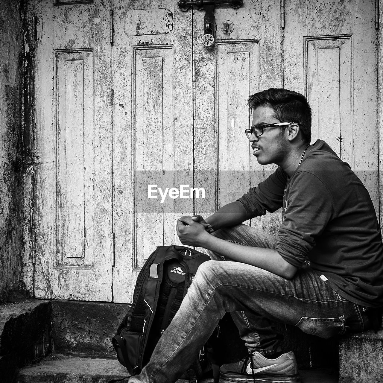 PORTRAIT OF YOUNG MAN SITTING ON WALL