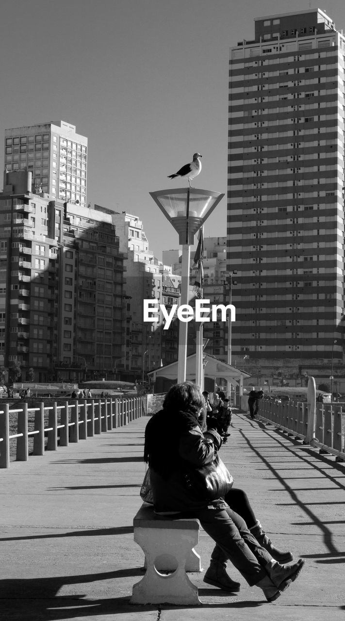 WOMAN WITH UMBRELLA AGAINST SKY IN CITY