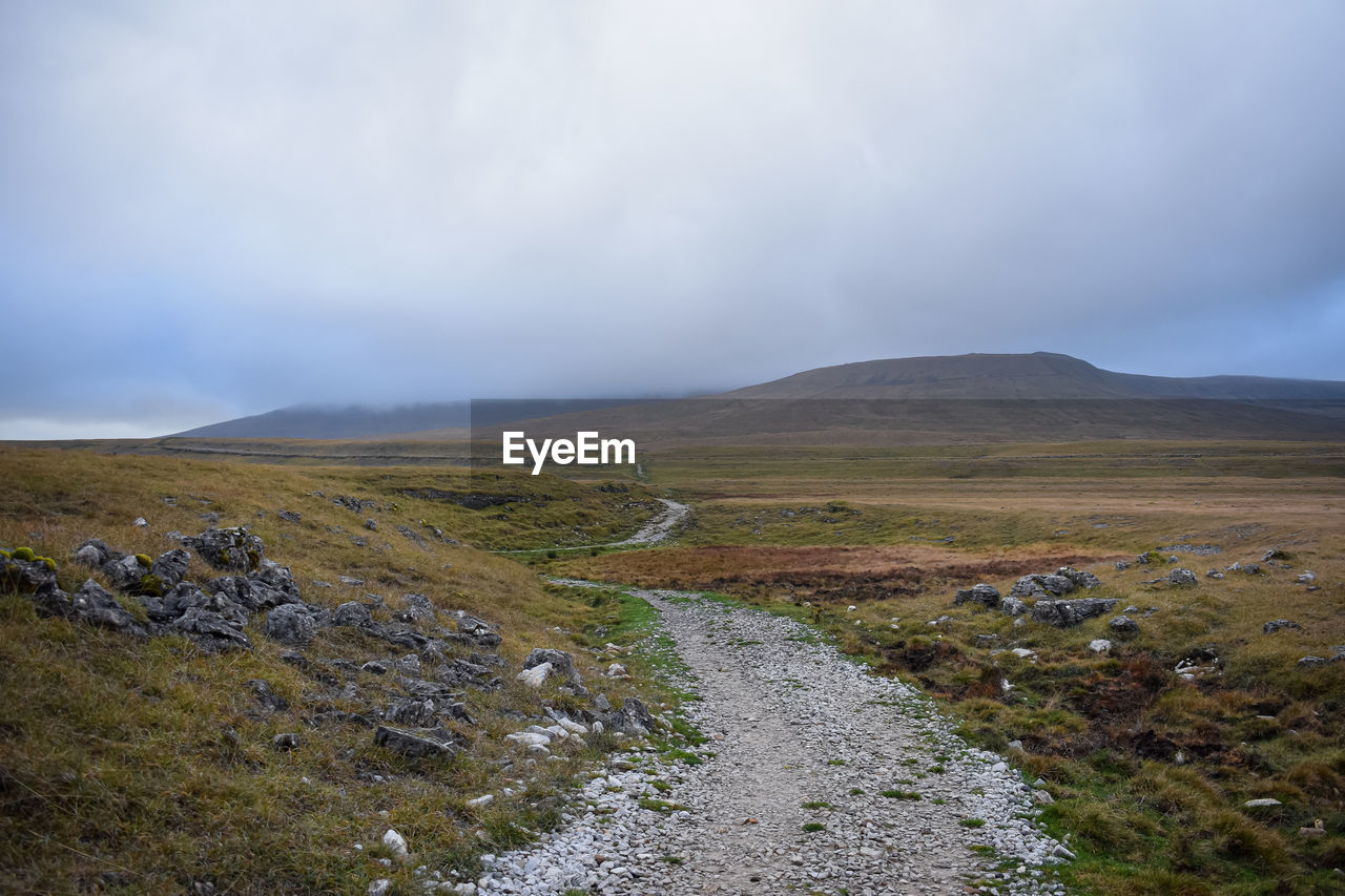 environment, landscape, cloud, wilderness, sky, mountain, highland, scenics - nature, nature, lake, beauty in nature, land, non-urban scene, ridge, no people, grass, tranquility, plant, travel, fog, travel destinations, tranquil scene, overcast, plateau, water, coast, outdoors, horizon, rural area, tundra, day, tourism, mountain range, remote, dramatic sky, rock, moor, road