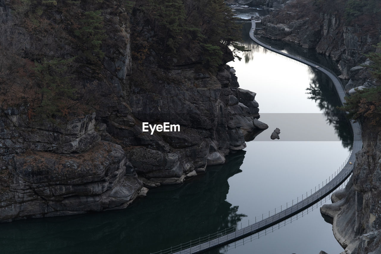 water, nature, rock, beauty in nature, scenics - nature, river, tranquility, reflection, tree, no people, rock formation, land, environment, travel destinations, mountain, landscape, outdoors, non-urban scene, travel, plant, architecture, tranquil scene, day, high angle view, tourism, cliff, forest, built structure, transportation, bridge, beach