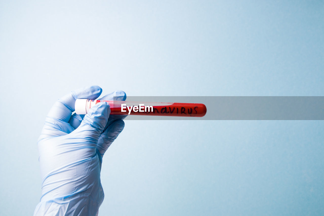 Close-up of hand holding umbrella against white background