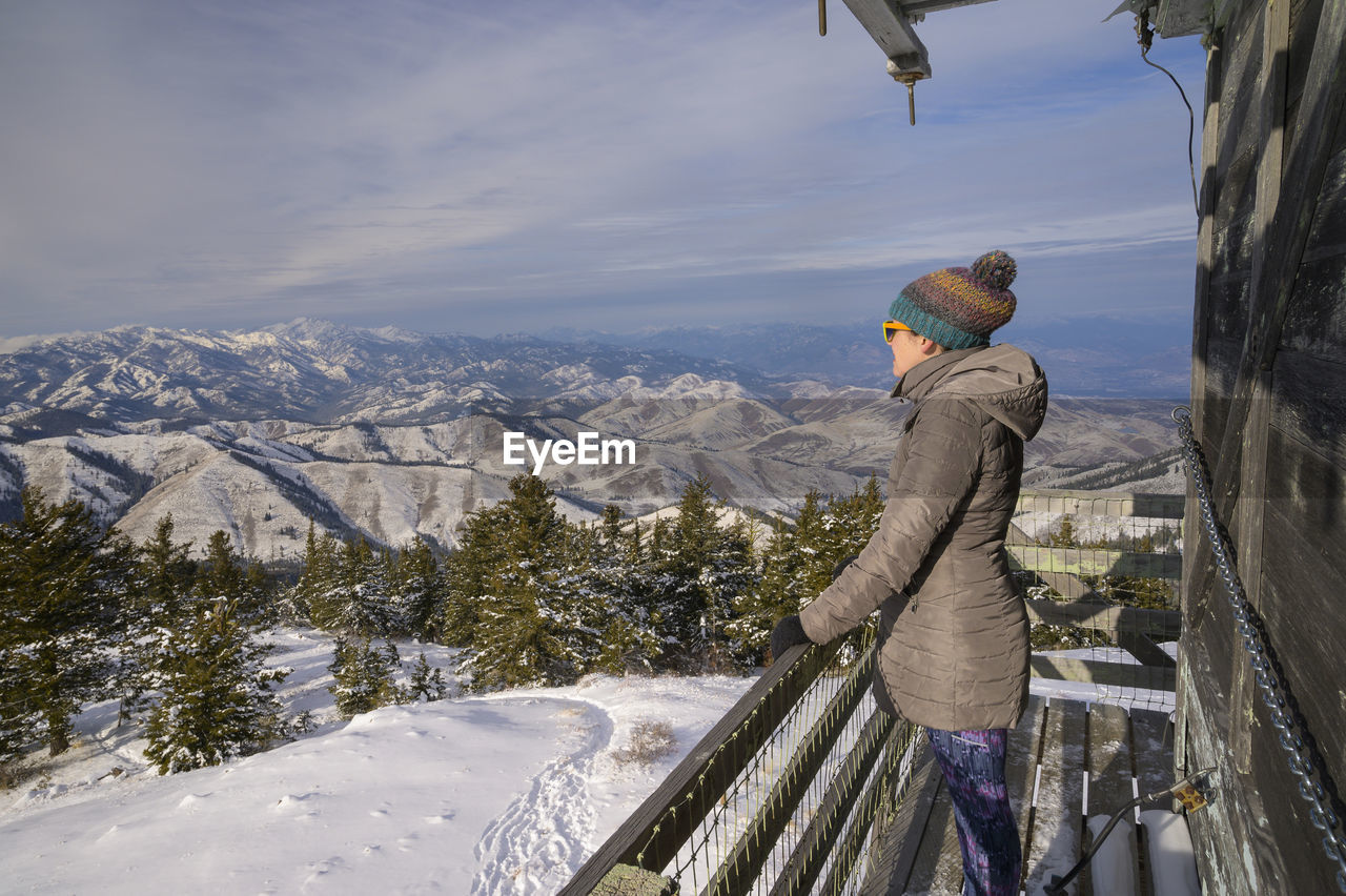Female looking into the distance from a fire lookout in the mountains