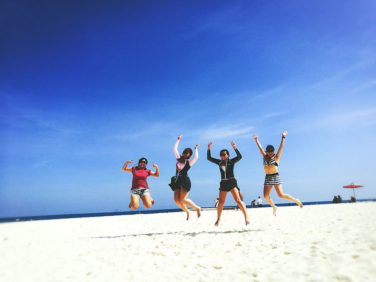 Happy friends jumping on sand at beach