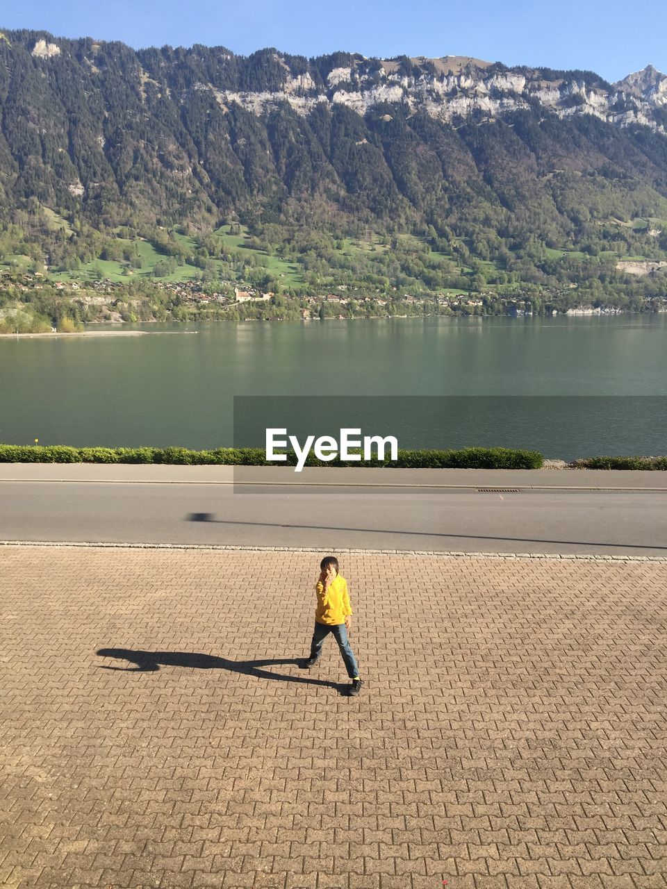 Boy standing on footpath against lake