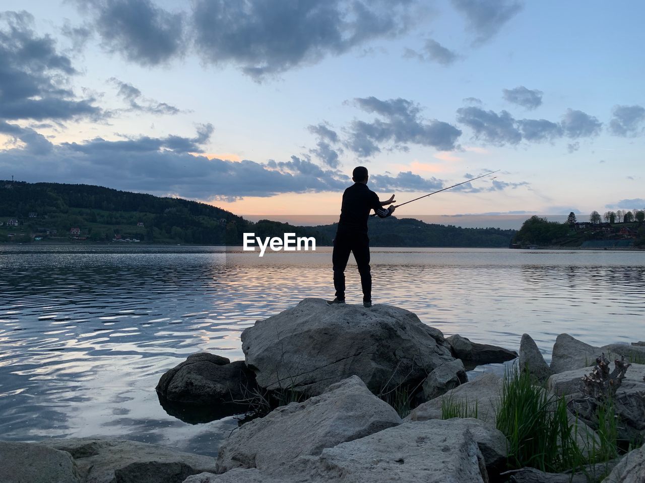 FULL LENGTH OF MAN STANDING ON ROCK AGAINST SKY DURING SUNSET