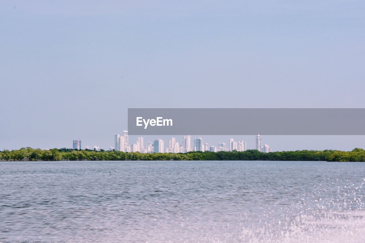 Scenic view of sea by city against clear sky