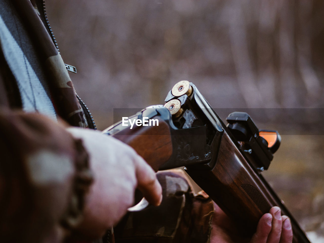 Midsection of man holding shotgun while standing outdoors