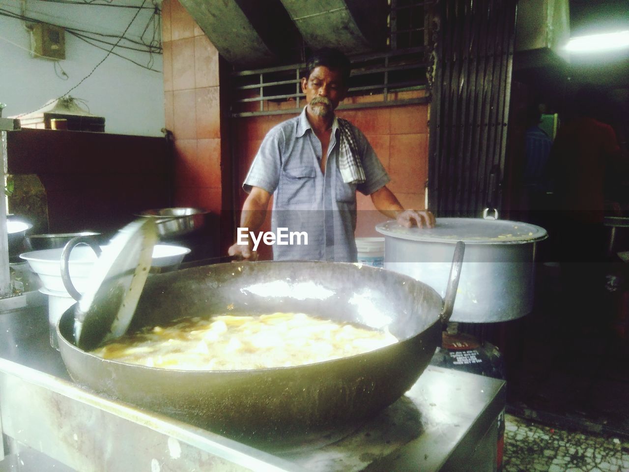 Vendor cooking food in large frying pan