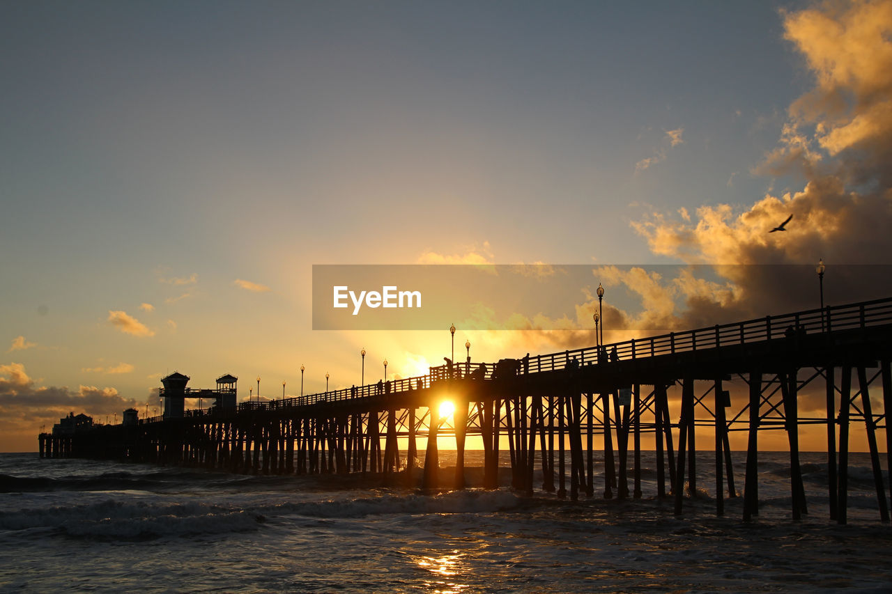 Sunset on the shore of the pacific ocean. oceanside pier highlighted. dusk and serenity.