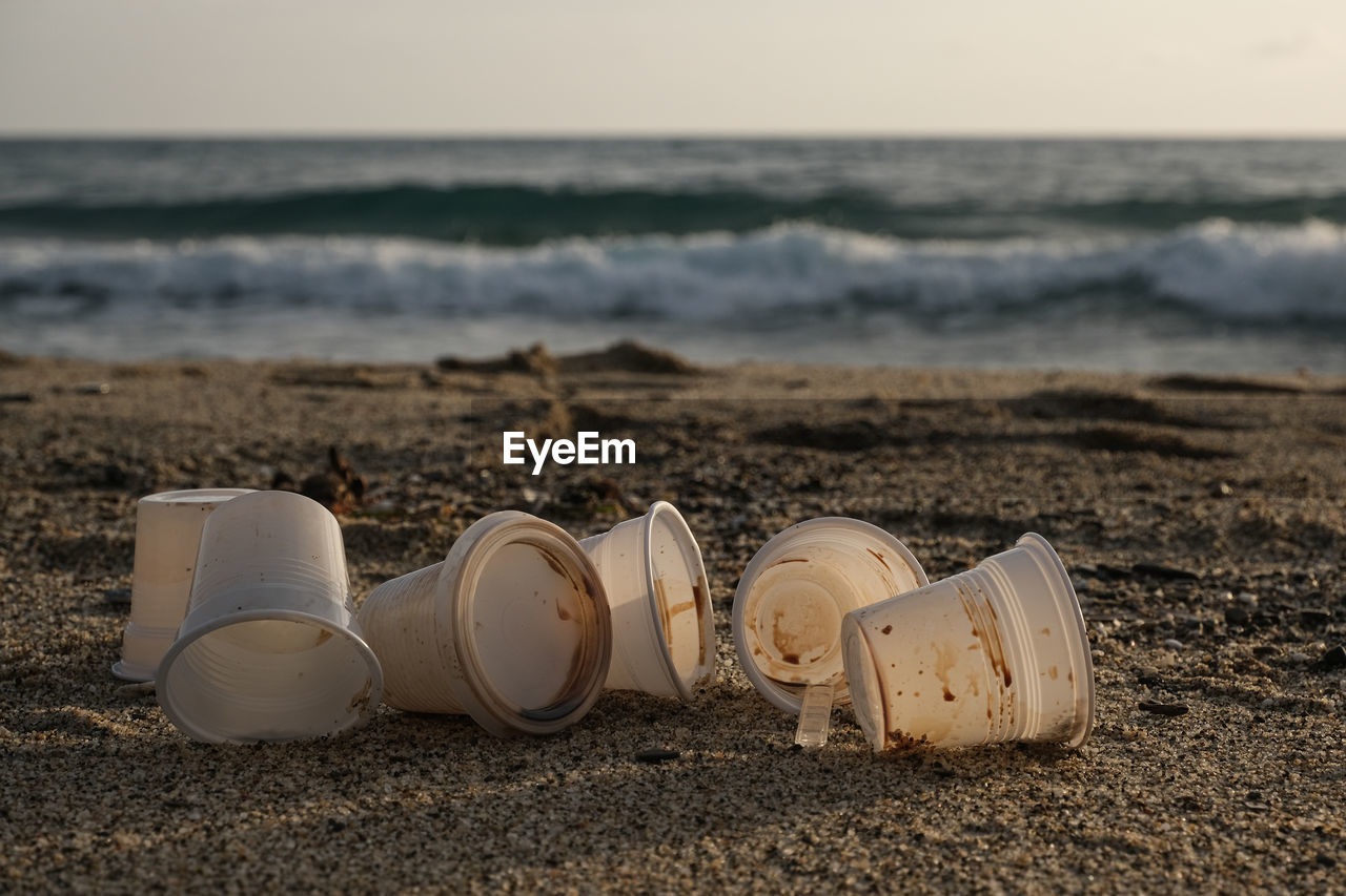 Disposable plastic dirty coffee cups discharged waste,throw pollution,sea shore