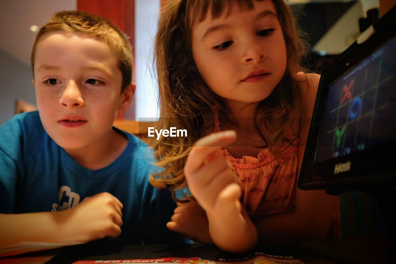 Close-up of siblings using digital tablet at table