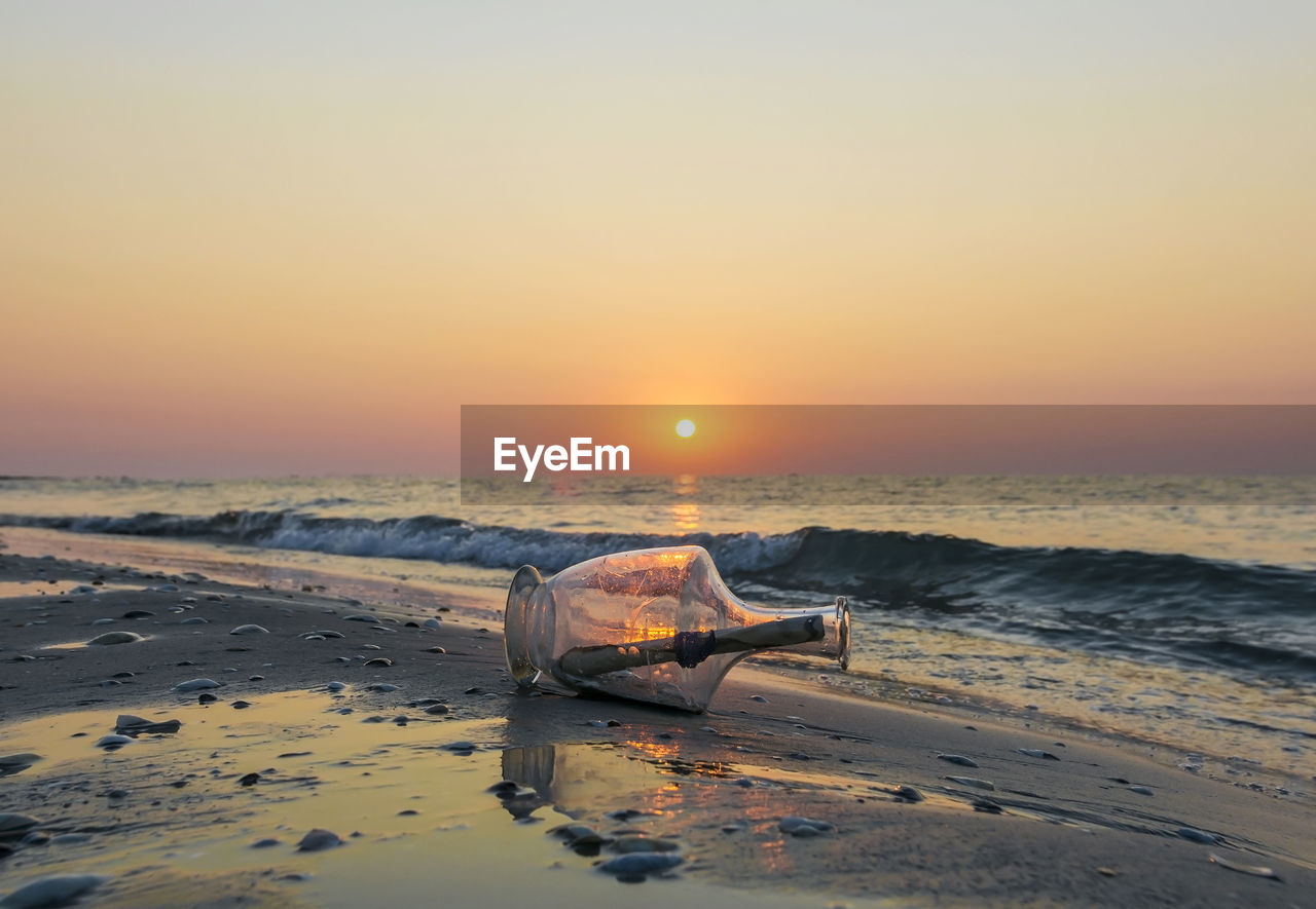 Message in a bottle on the beach at sunset