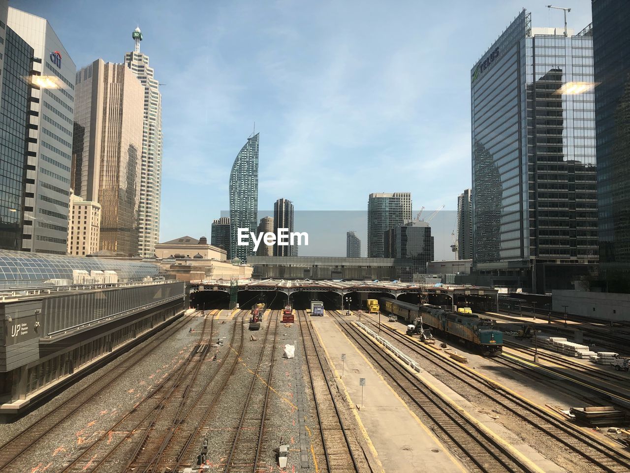 RAILROAD TRACKS BY BUILDINGS AGAINST SKY IN CITY