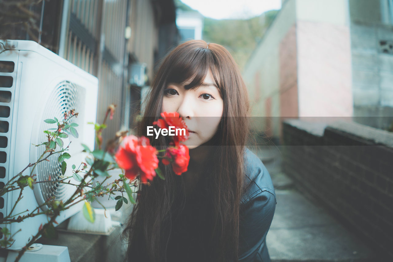 PORTRAIT OF BEAUTIFUL WOMAN WITH RED FLOWER IN MOUTH