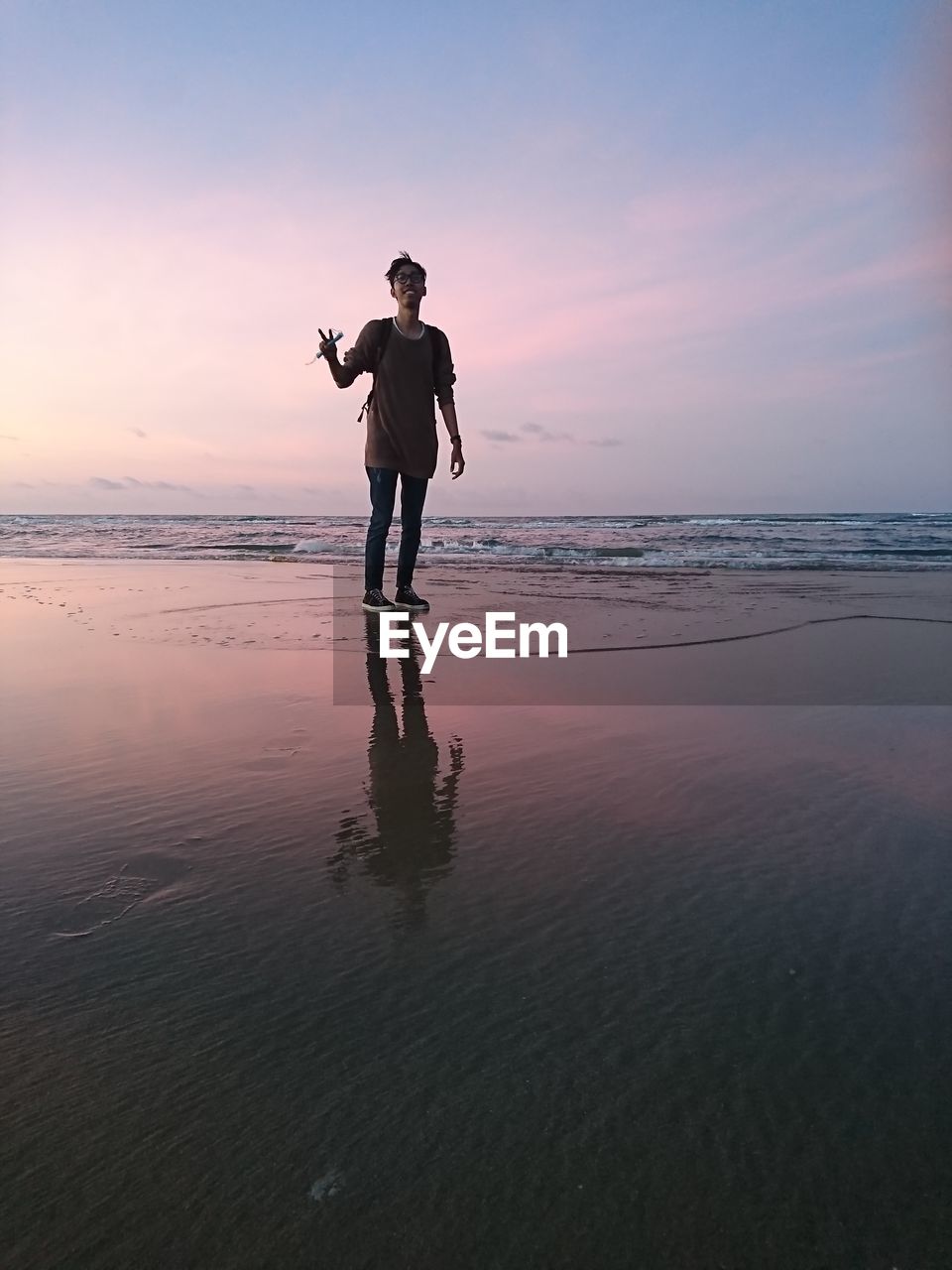 Full length of man standing at beach during sunset