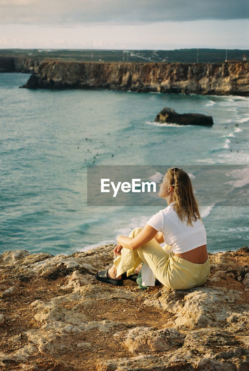 Woman sitting on rock at sea shore