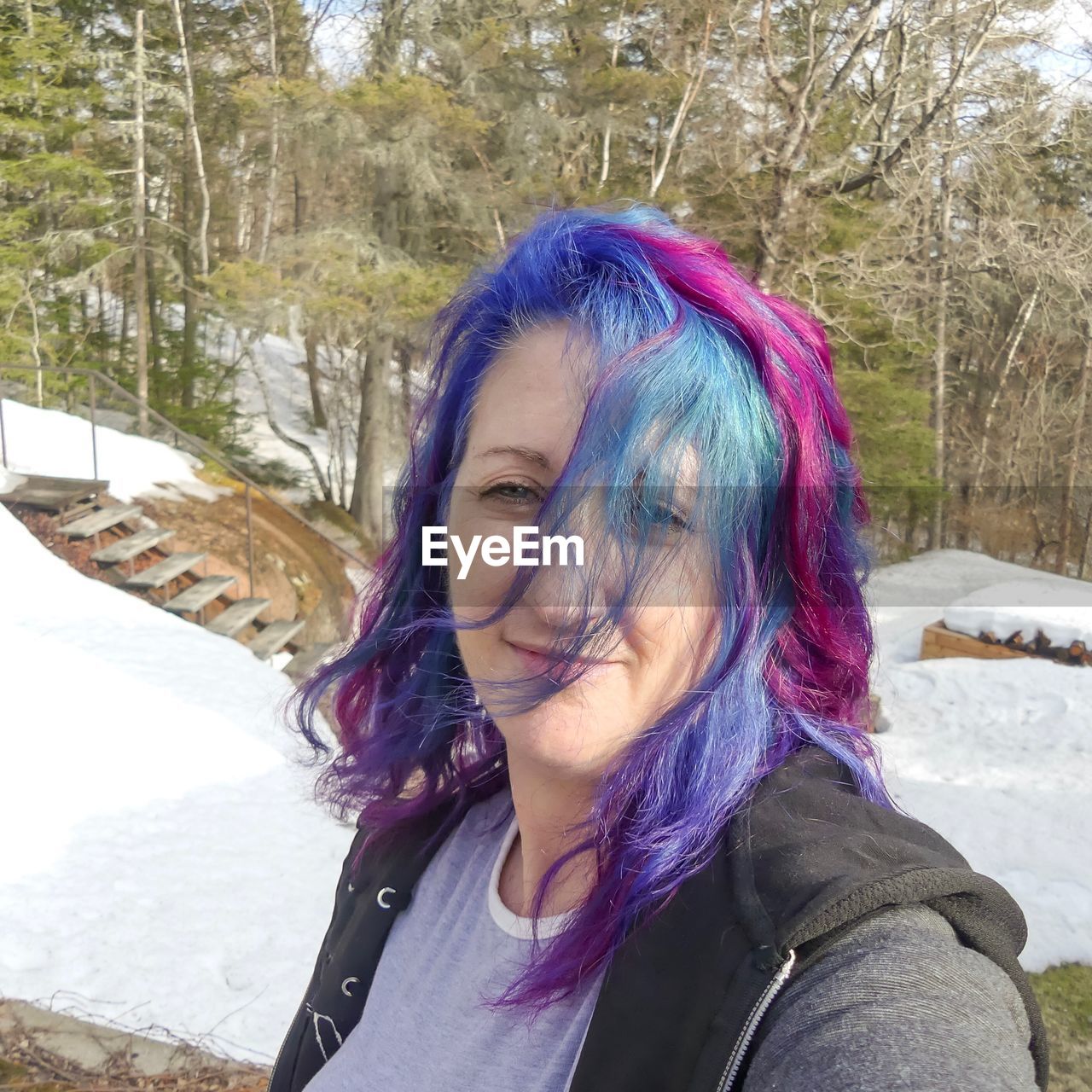Portrait of smiling woman with dyed hair on snow