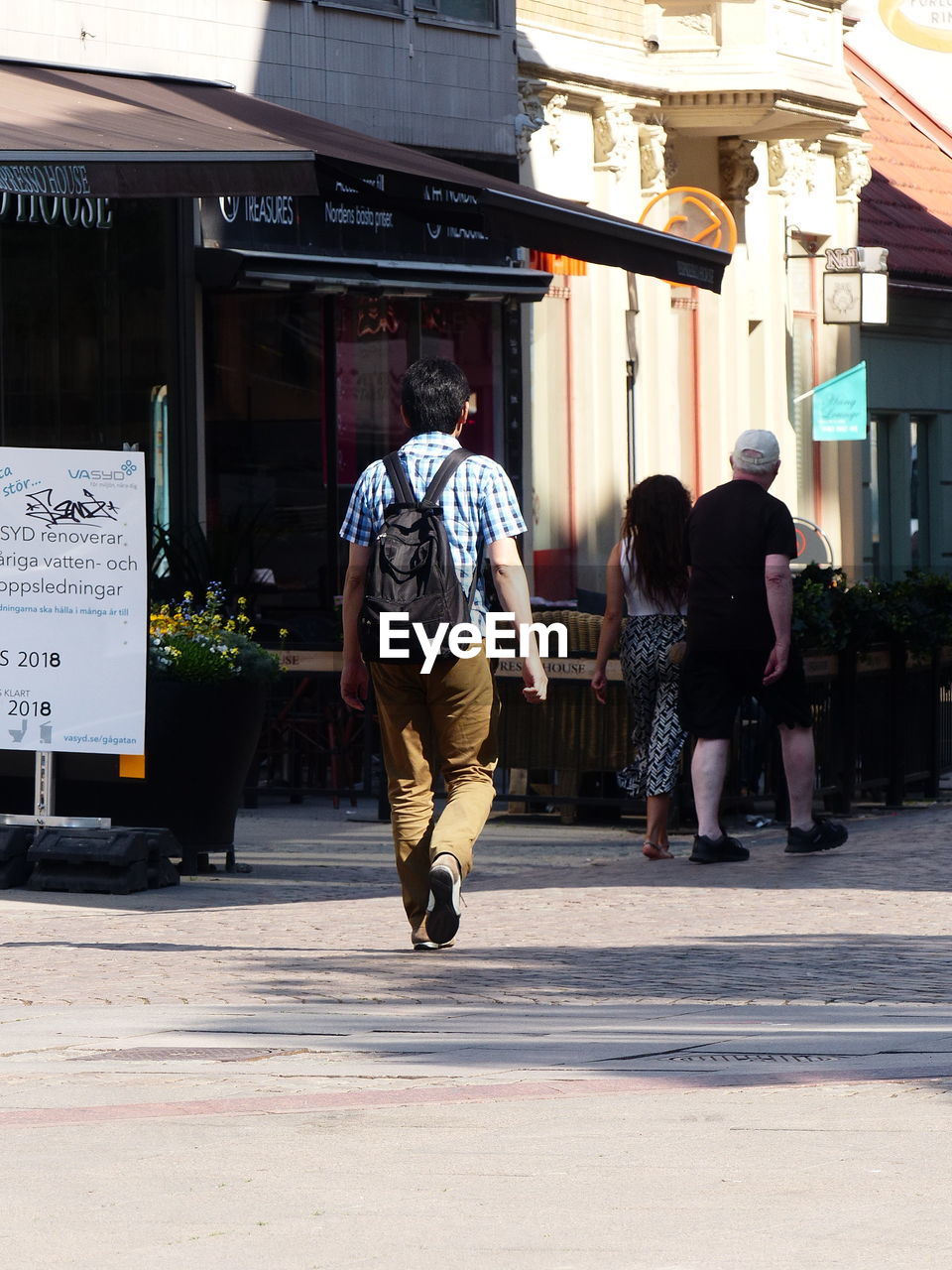 FULL LENGTH REAR VIEW OF PEOPLE WALKING ON FOOTPATH