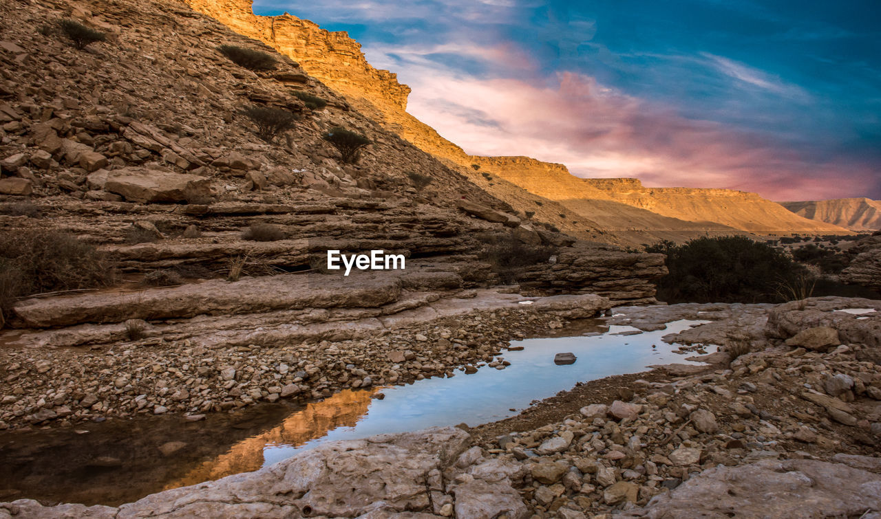 Rock formations by lake against sky