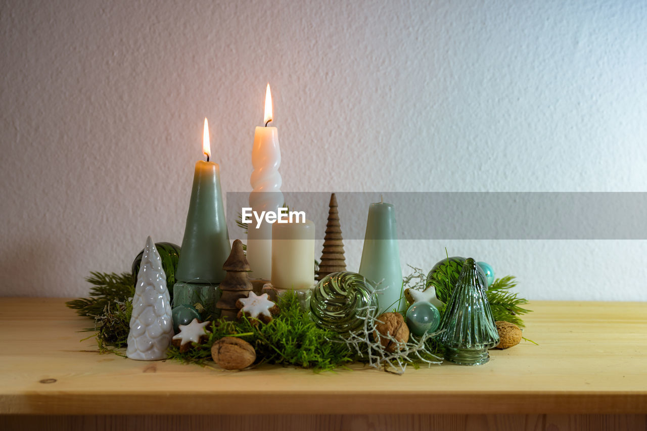 candle, flame, fire, burning, indoors, nature, plant, celebration, heat, illuminated, interior design, no people, table, decoration, candle holder, lighting, wood, green, holiday, food and drink, wall - building feature, food, home interior, still life, domestic room, christmas, candlestick holder
