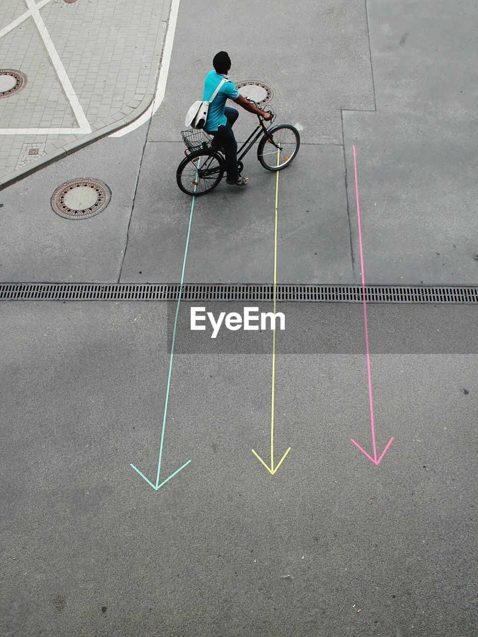 High angle view of man cycling over arrows symbols on street