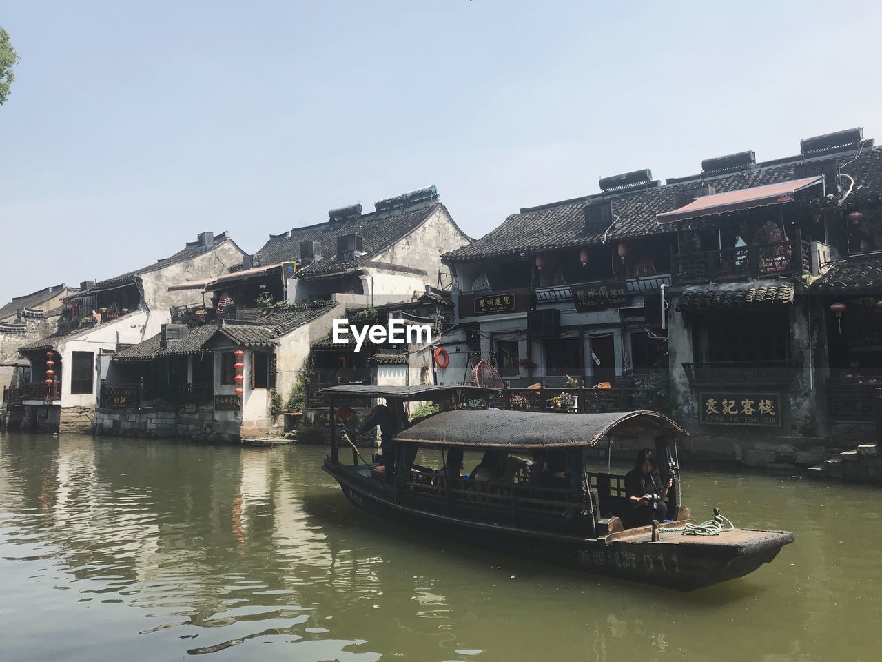 Boats in river by buildings in city against sky