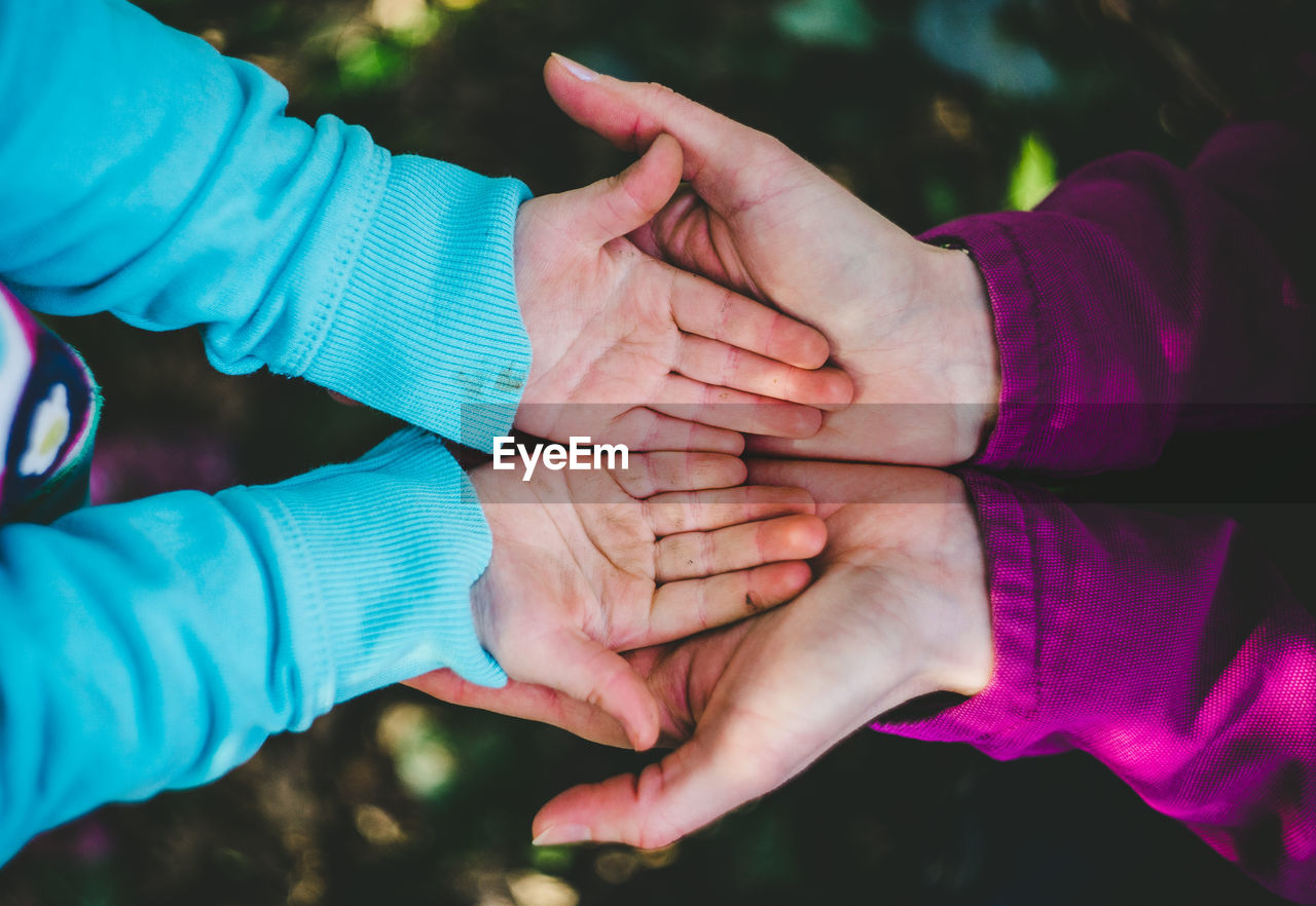 Directly above shot of mother and child hands playing outdoors