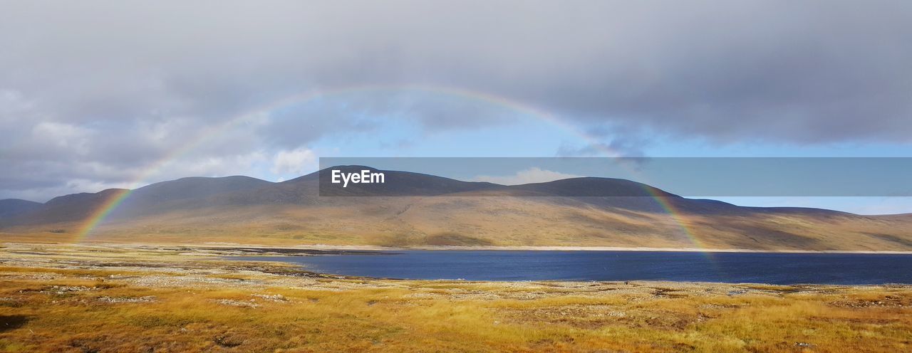 Scenic view of rainbow over mountains against sky