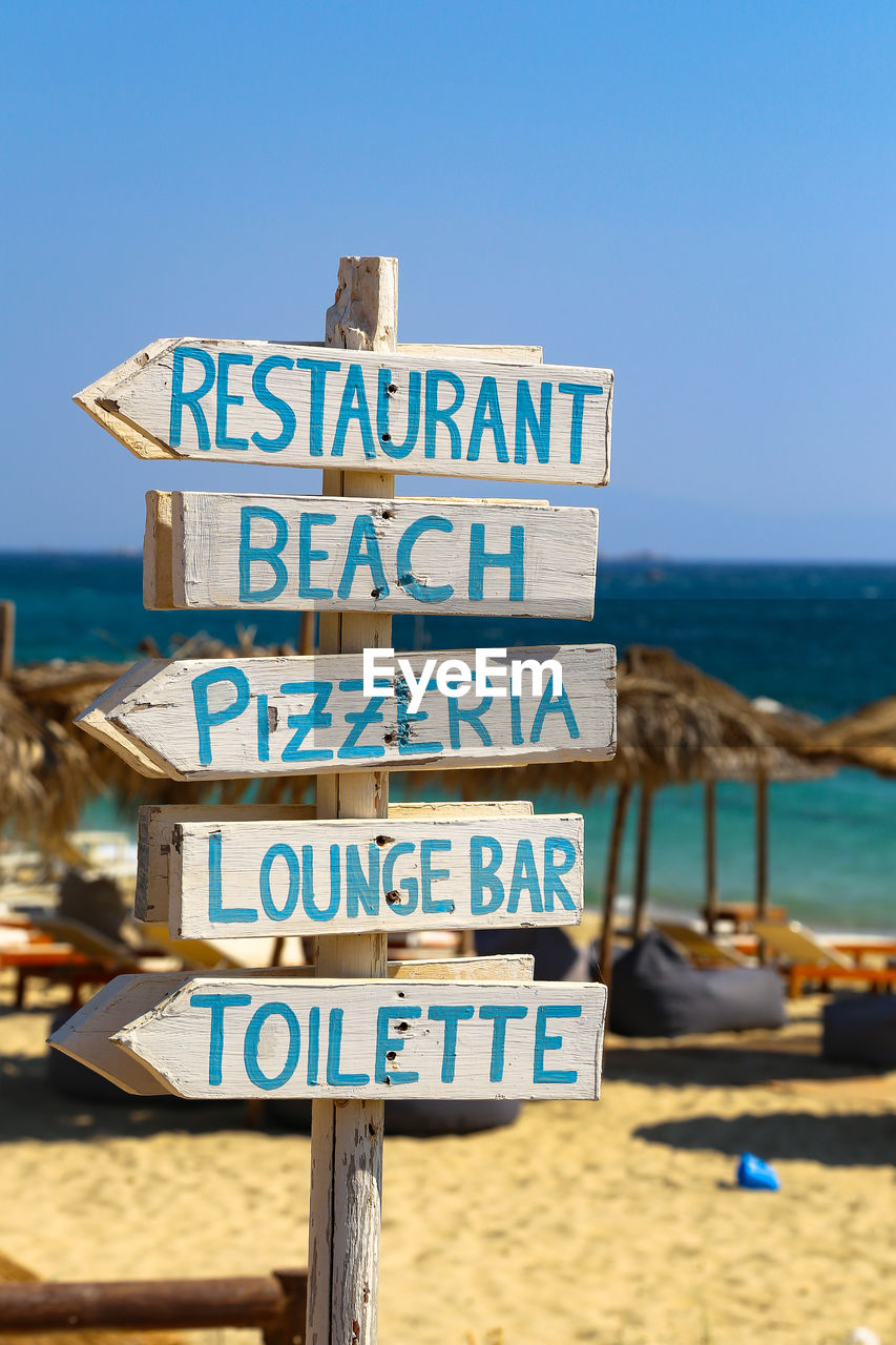 Information sign on beach against clear sky