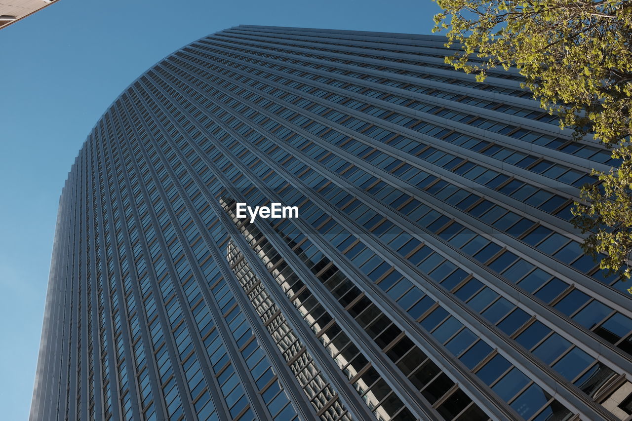 Low angle view of modern office building against blue sky