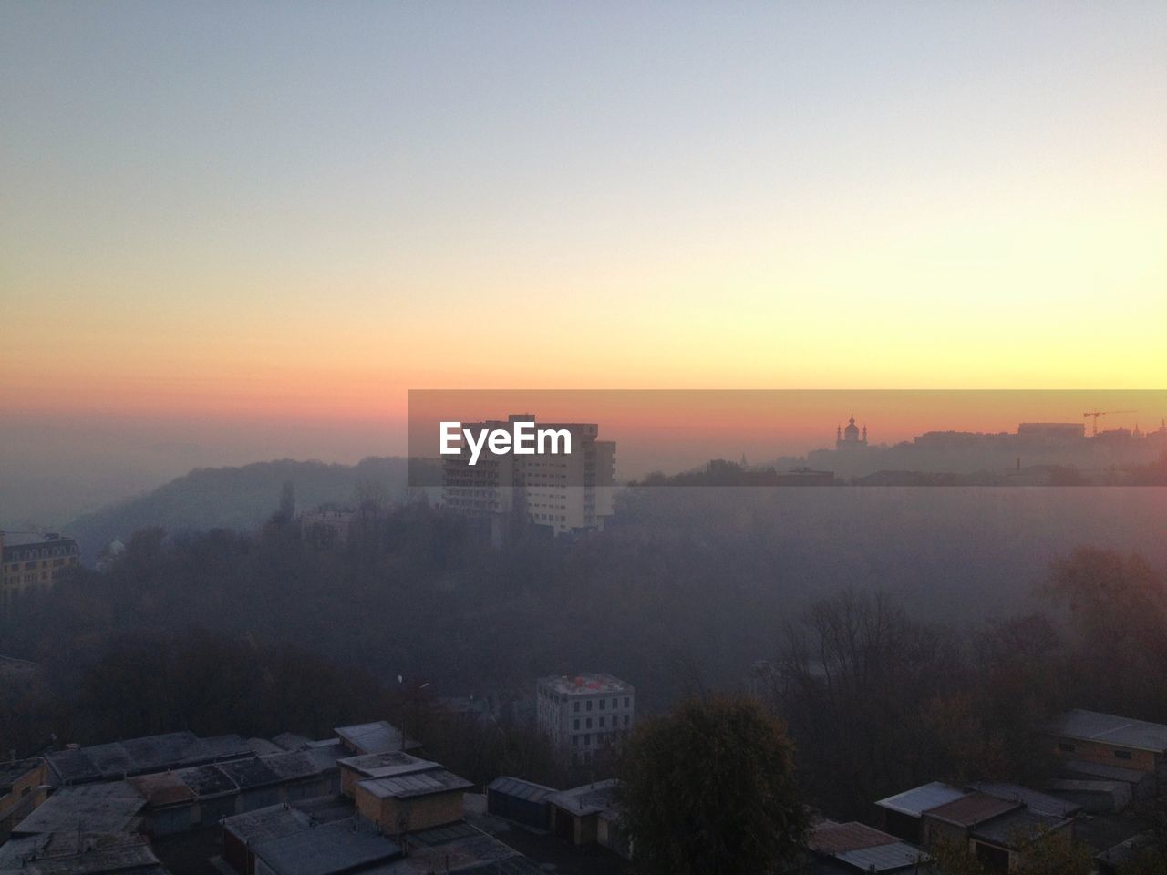 HIGH ANGLE VIEW OF CITYSCAPE AGAINST SKY AT SUNSET