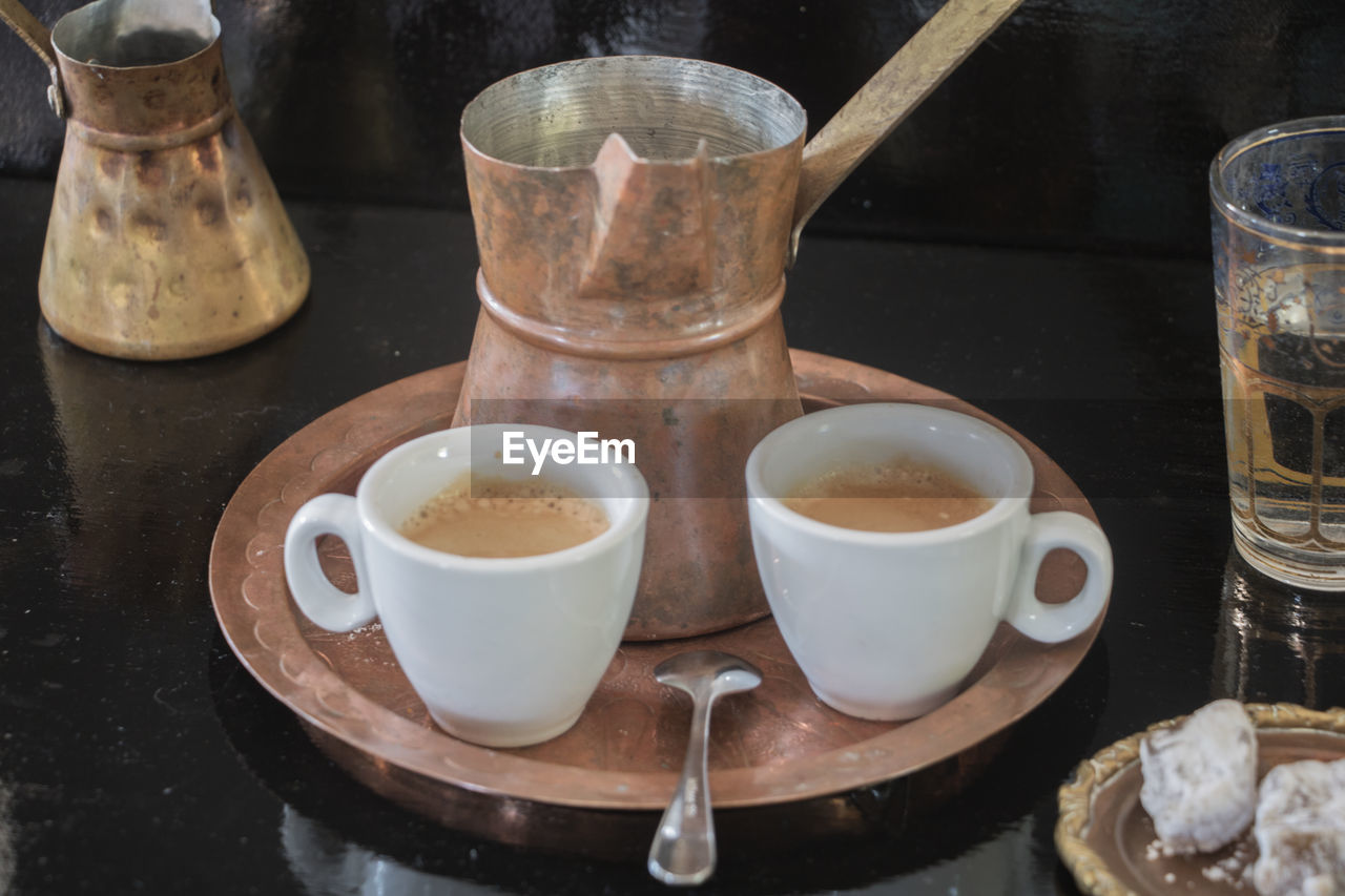 High angle view of tea cups by kitchen utensils on table