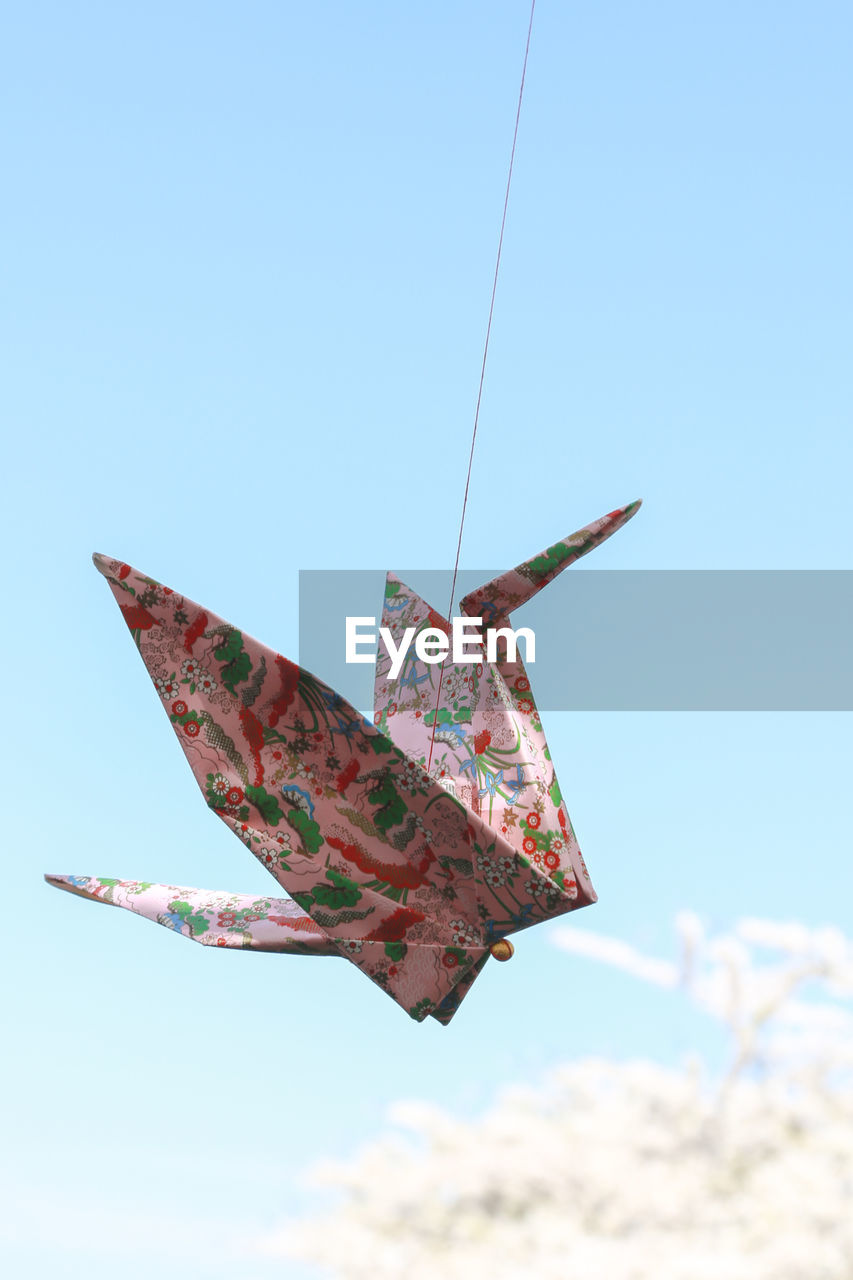 Low angle view of paper crane against clear blue sky