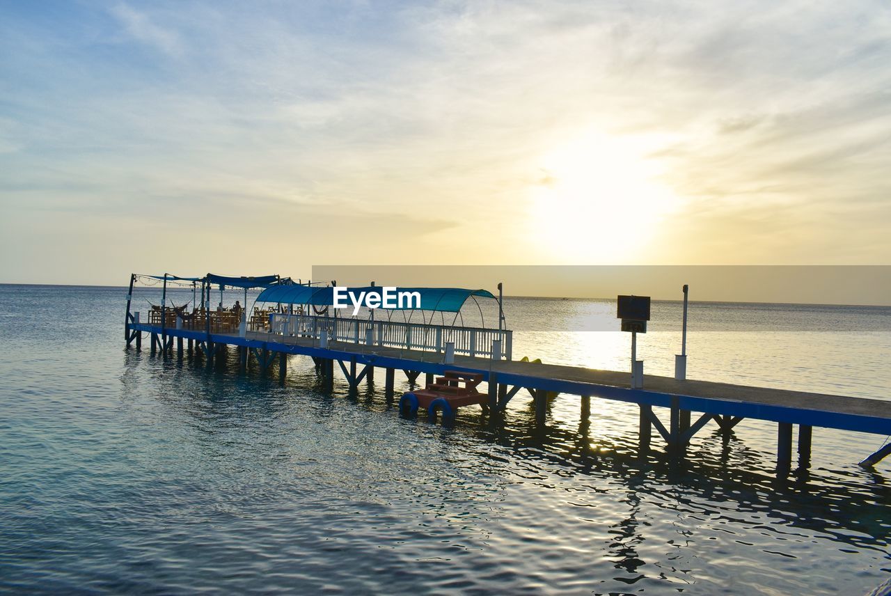 Pier on sea against sky during sunset