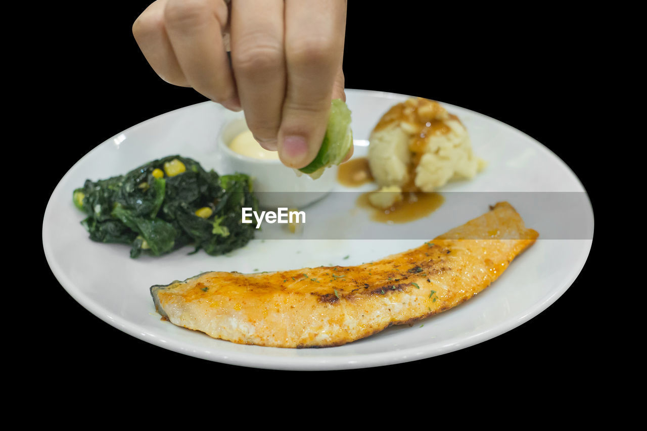 food, food and drink, plate, dish, hand, one person, black background, healthy eating, freshness, meal, produce, indoors, wellbeing, fish, vegetable, cuisine, breakfast, studio shot, fast food, close-up, green