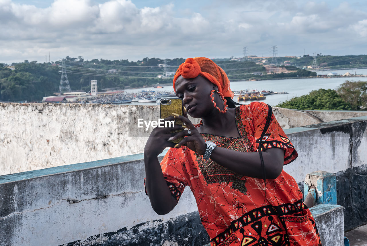 African woman photographing while standing outdoors