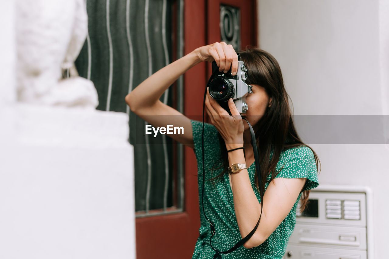 Young woman photographing with film camera