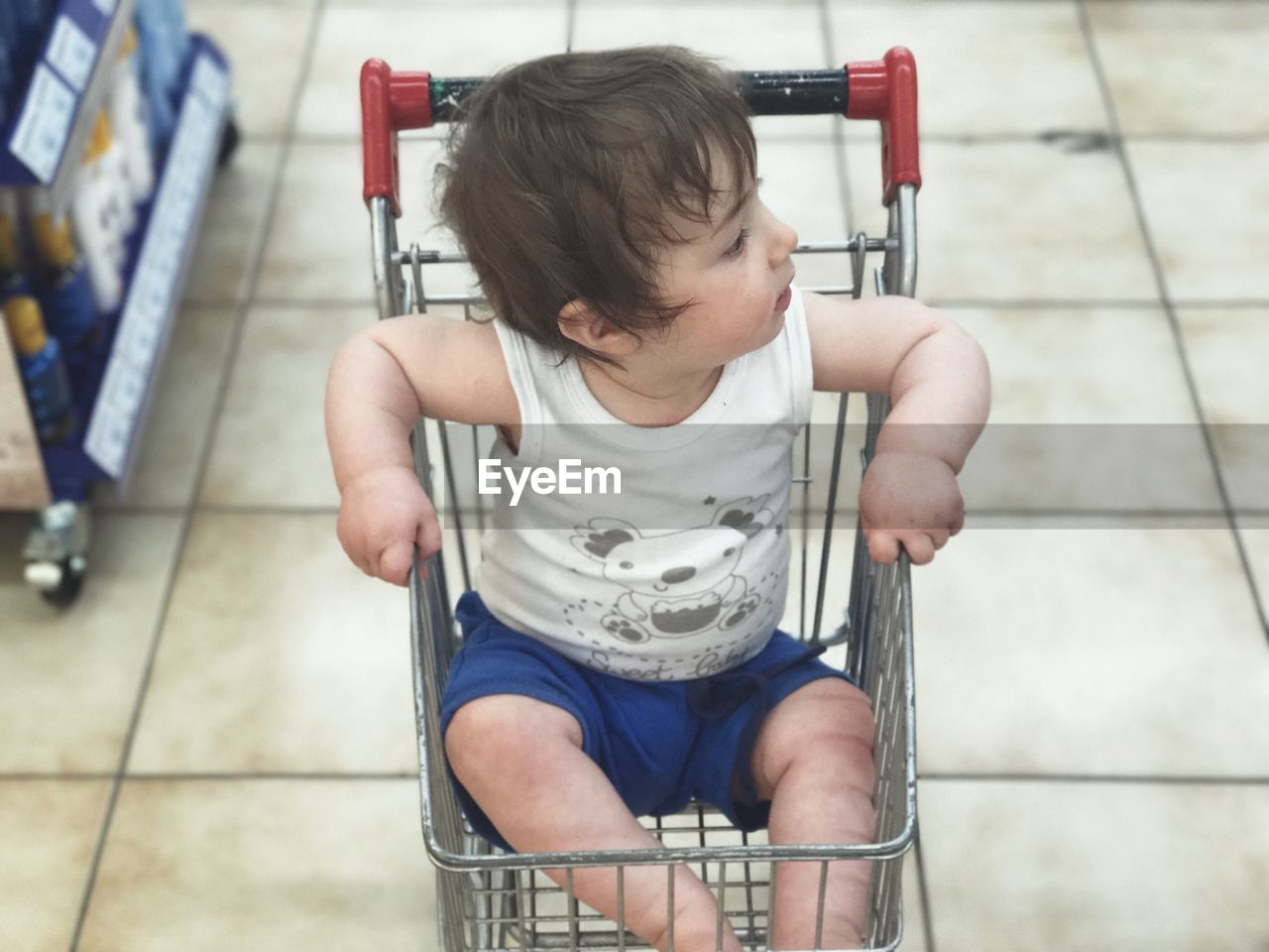 High angle of baby boy sitting in shopping cart