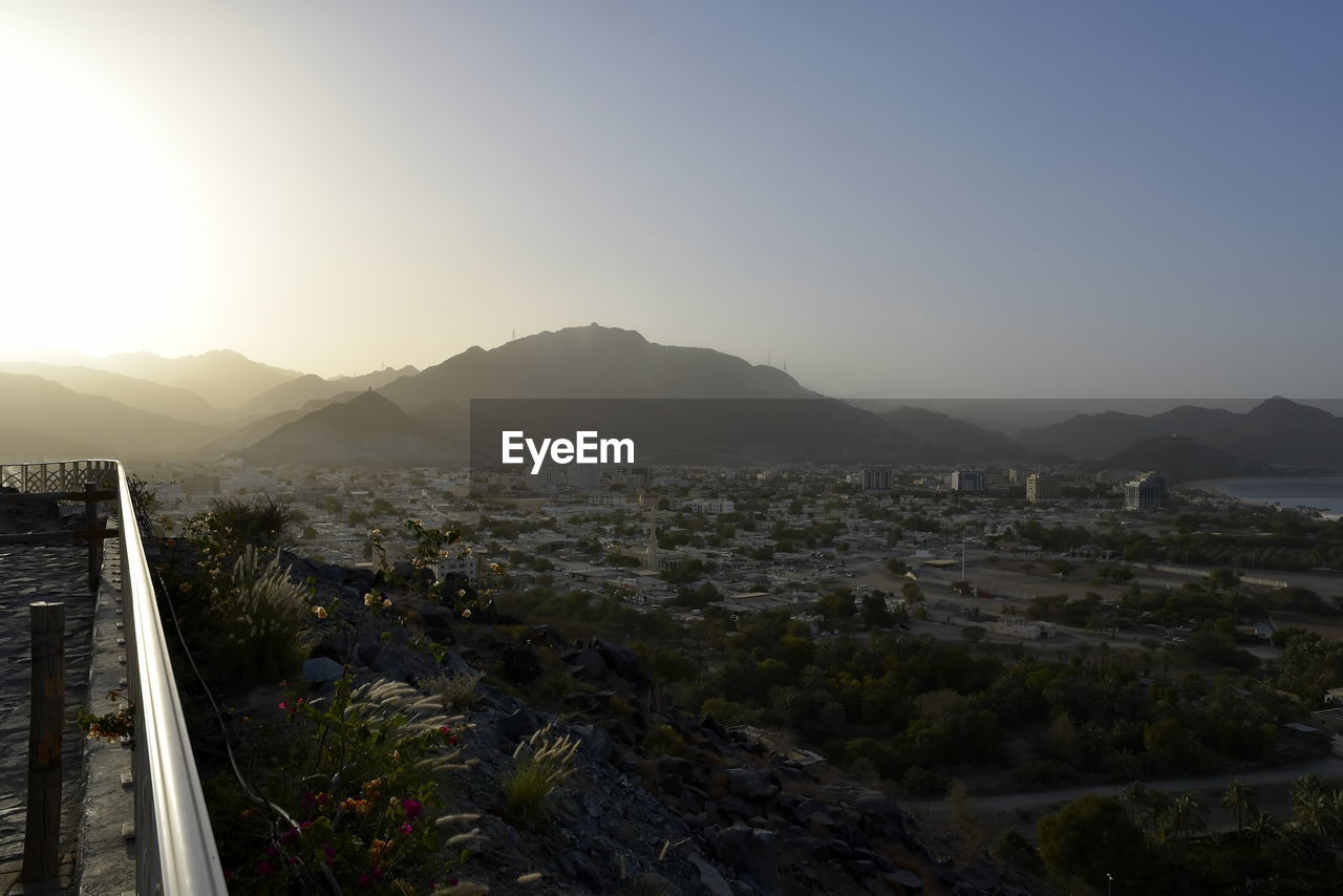 HIGH ANGLE VIEW OF TOWNSCAPE BY MOUNTAINS AGAINST SKY