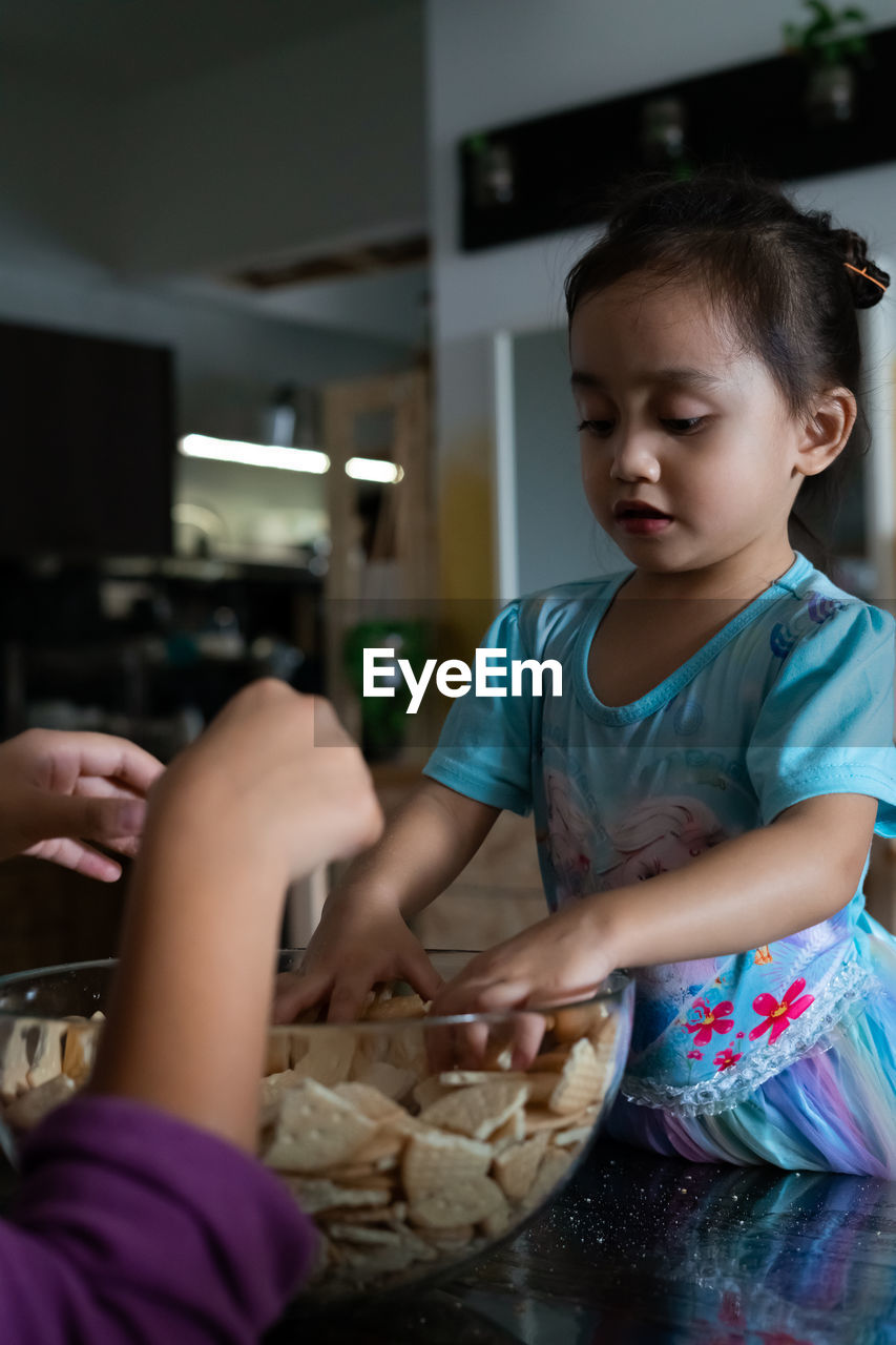 Kids making kek batik or malaysian triple chocolate dessert. crushing the cookies into tiny pieces.