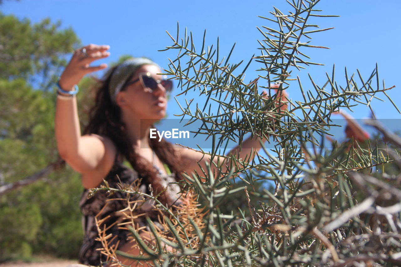 LOW ANGLE VIEW OF WOMAN AGAINST SKY